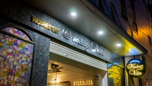 A hotel entrance with a sign reading "Homestay Hoang Van" and a colorful stained glass window.