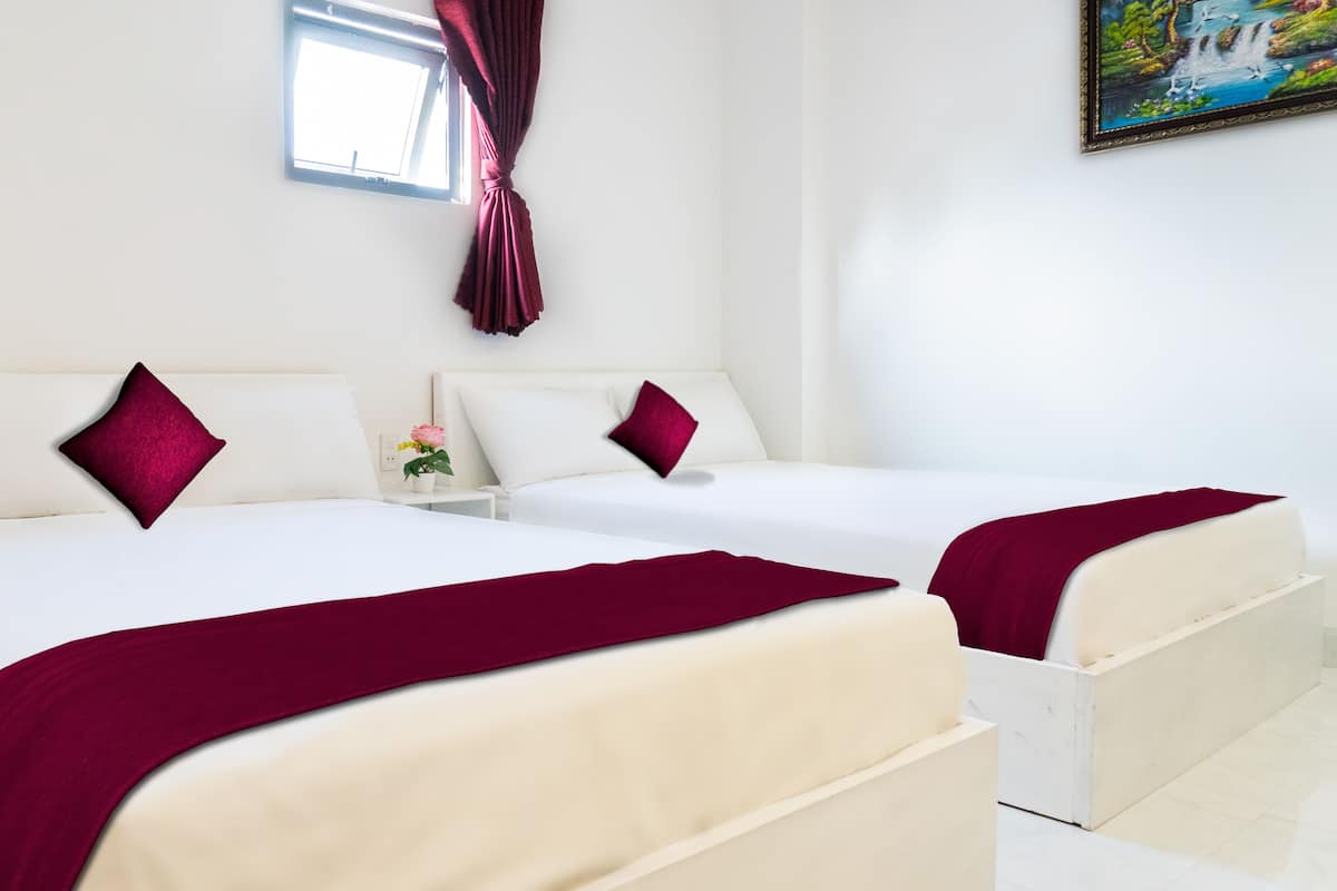 A hotel room with two beds, white bedding, and red throw pillows.