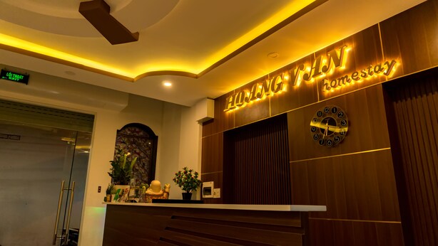 A hotel reception desk with a modern design, a clock, and a sign that reads "HOMESTAY".