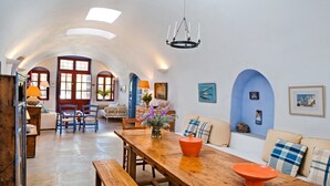 Un vaste espace dédié à la salle à manger, avec une table en bois, des bancs et un lustre.
