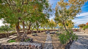Un sentier de pierres qui traverse un jardin planté d’arbres et offre une vue sur la mer.
