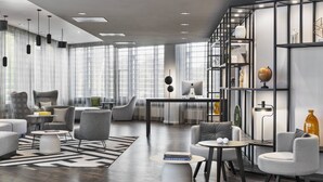Una sala de estar moderna con un sofá, sillones, una mesita de centro y una estantería.