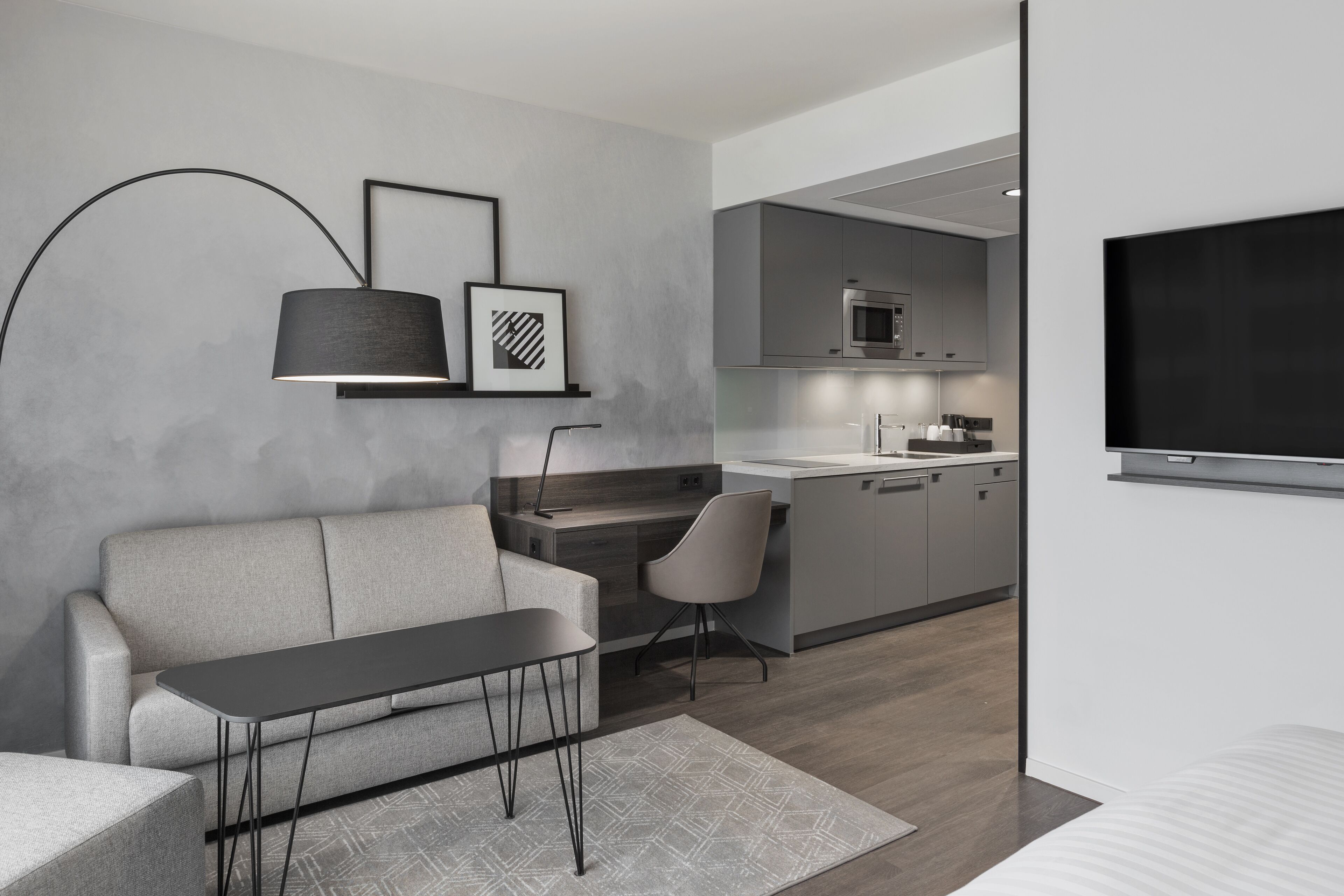 Un espacio habitable moderno con sofá, mesa de comedor, televisor y zona de cocina.