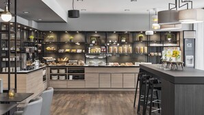 Una cocina moderna con armarios de madera, una isla central, taburetes de bar e iluminación colgante.