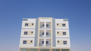 Un edificio de varios pisos con una fachada simétrica, que presenta ventanas y balcones regularmente distribuidos.