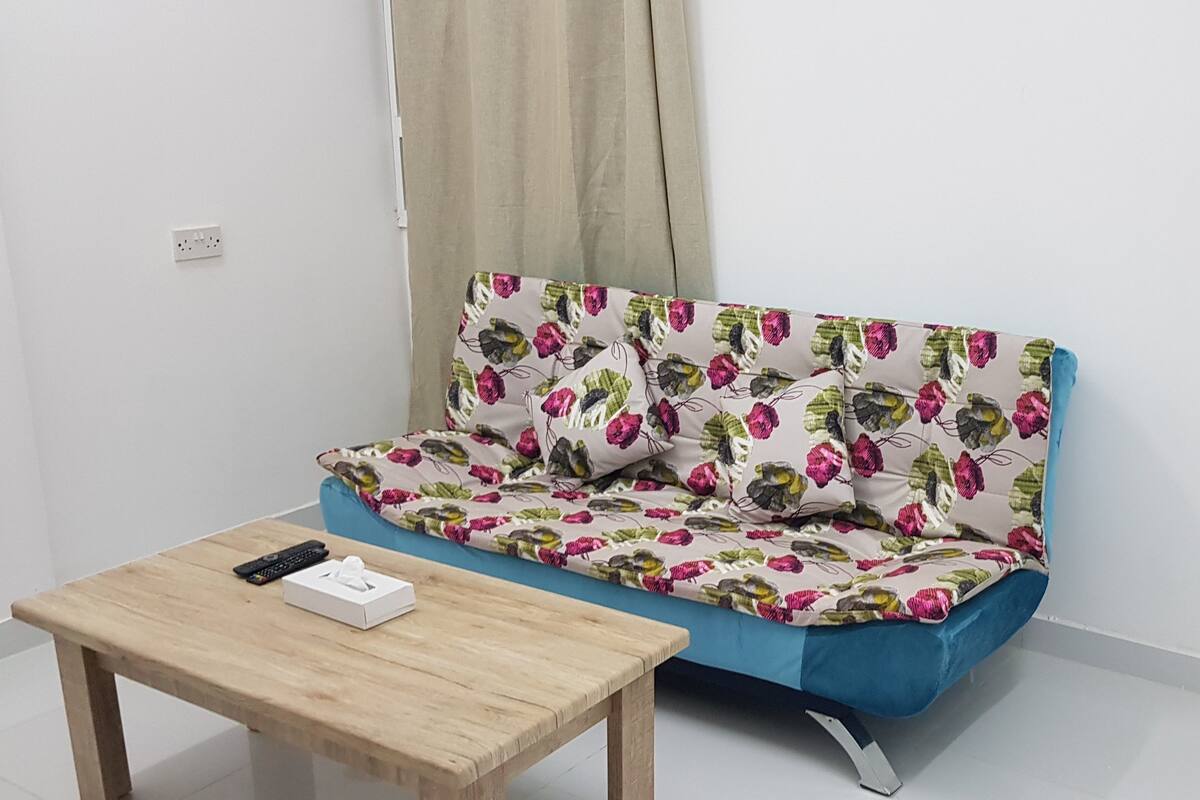 Una habitación pequeña y acogedora con un sofá azul y una mesa de madera.