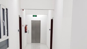 Un pasillo limpio y moderno con un suelo de baldosas brillantes, un extintor de incendios montado en la pared y una puerta al final.