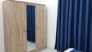 Una habitación con un armario de madera, un espejo y cortinas azules.