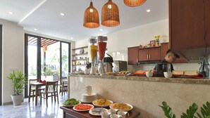 A modern kitchen with a dining area, featuring a buffet setup with various dishes and drinks. - Saclo Villa and Hostel (Da Nang)