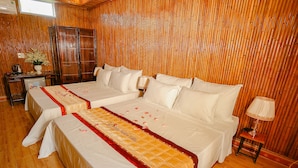 A hotel room with two beds, wooden flooring, a desk with a computer, and a bamboo wall. - Windy Fields Villa (Nam Hoa Lu)