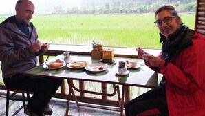 Two people sitting at a table with a view of a green field. - Windy Fields Villa (Nam Hoa Lu)