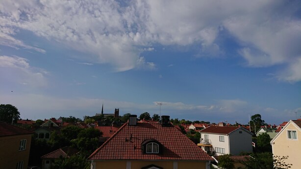 Een woonwijk met rode dakpannen, een kerktoren en een heldere lucht.