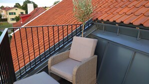 Een balkon met rieten meubilair en een kleine boom.