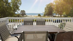 A deck with a table and chairs overlooking a beach.