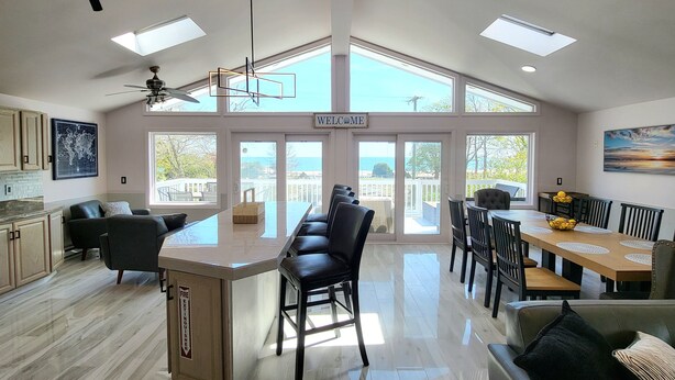 A spacious kitchen with a central island, large windows, and a view of the sea.