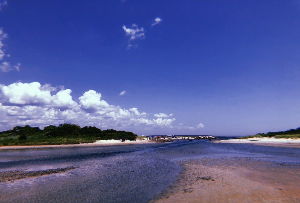 Une plage sous un ciel dégagé, avec une indication de date et d’heure : 7h14, 1998.