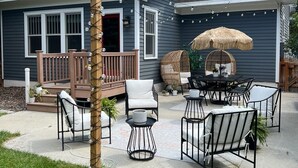 A two-story house with a covered patio area featuring outdoor furniture and a thatched umbrella. - Cody's Downtown Den - DOWNTOWN - New listing & Pets Welcomed! (Cody)