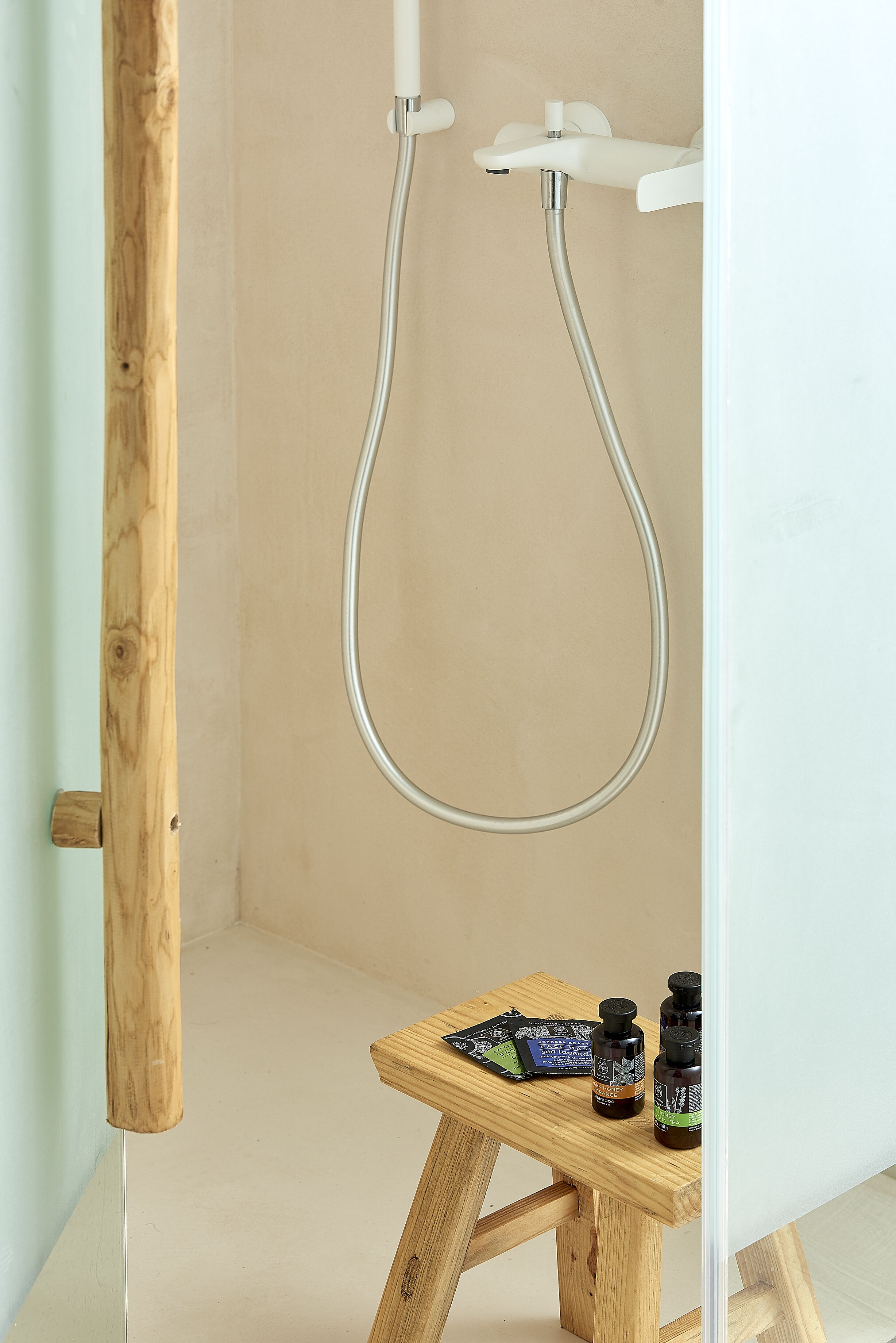 A shower with a wooden stool and bottles of personal care products.