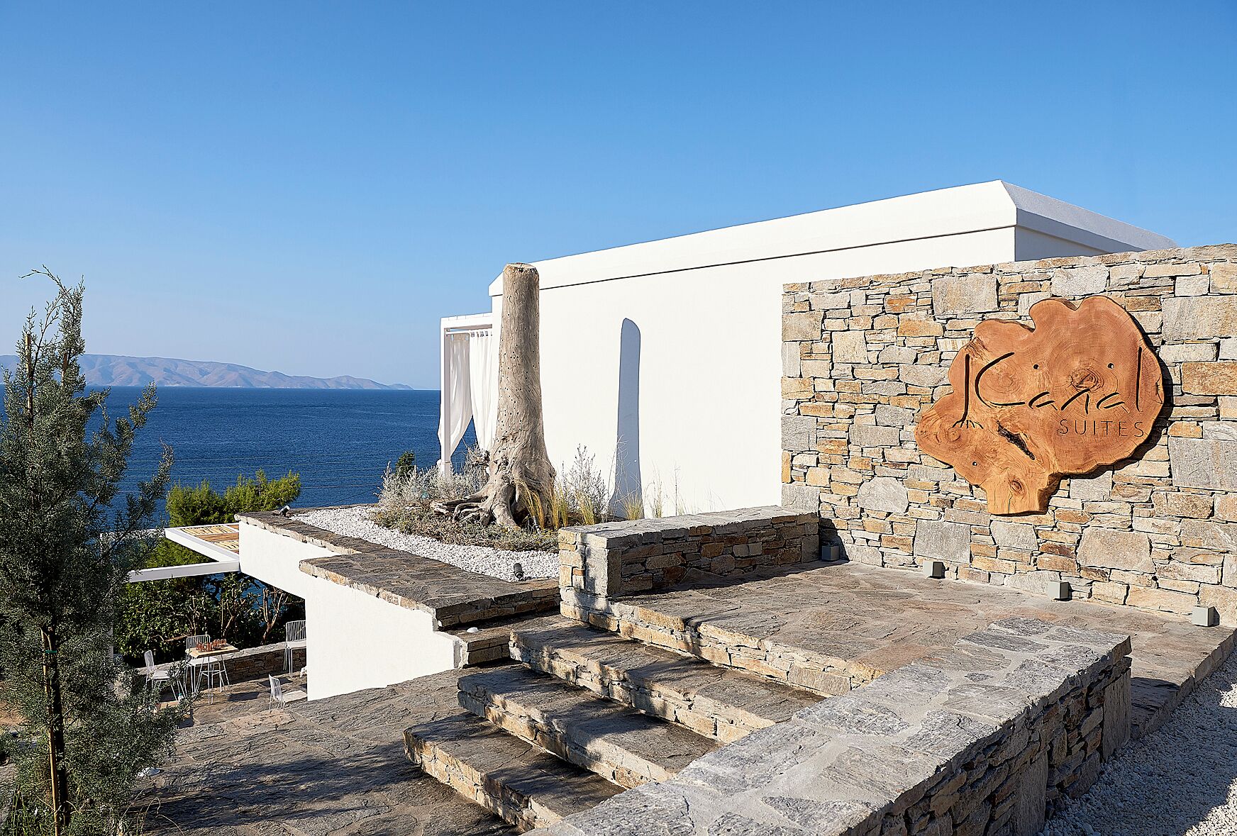 A stone staircase leading to a white building with a stone wall sign reading "J.C. & J. SUITES".