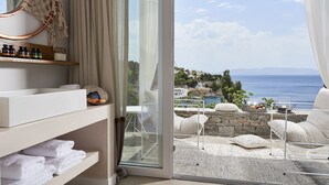 Un balcón con vistas al mar, una cama blanca y un estante con artículos de aseo.