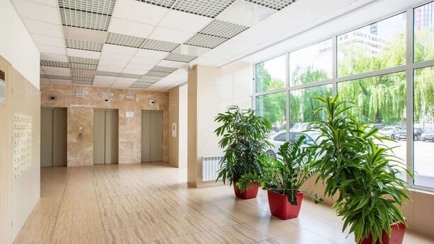 A spacious lobby with a tiled floor, large windows, and potted plants. - Comfortable Studio in the Center | Parking and Balcony (Warszawa)