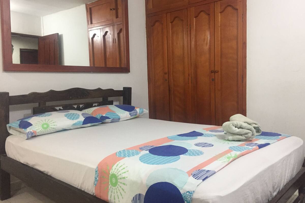 A bedroom with a wooden bed, a large mirror, and a wardrobe.