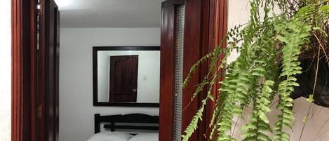 Una habitación de hotel con una cama, un espejo en la pared y una planta en maceta.