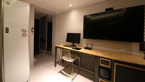 A modern kitchen with a built-in refrigerator, a wooden countertop, a black monitor, and a wall-mounted TV. - Hotel Cheese Ulsan Samsan (Ulsan)