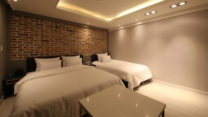 A modern hotel room with two beds, a brick accent wall, recessed ceiling lighting, and a small table. - Hotel Cheese Ulsan Samsan (Ulsan)