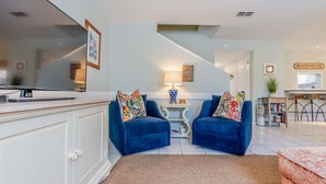 Een moderne woonkamer met twee blauwe fauteuils, een salontafel en een trap die naar een ander niveau leidt.