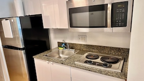 A kitchen with a stainless steel refrigerator, a microwave, a sink, and a stove.