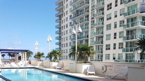 A swimming pool with lounge chairs and a high-rise building in the background.