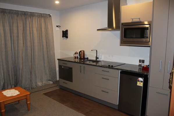 A compact kitchen with a built-in microwave, a dishwasher, and a coffee maker. - The Mackenzie Suites (Lake Tekapo)