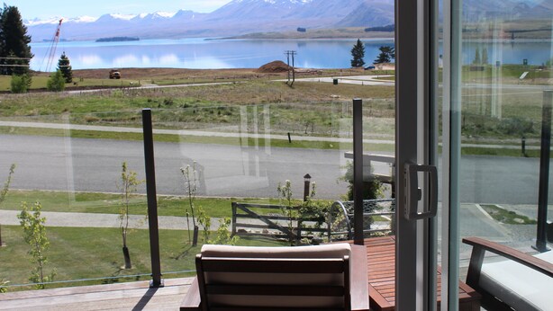 Una habitación con un ventanal grande que ofrece vistas a un lago y montañas.