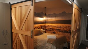 Un dormitorio con una cama grande, paredes de madera y un mural con un paisaje de montaña.