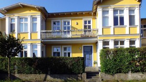 Un bâtiment jaune doté d’un balcon, de grandes fenêtres et d’une porte.