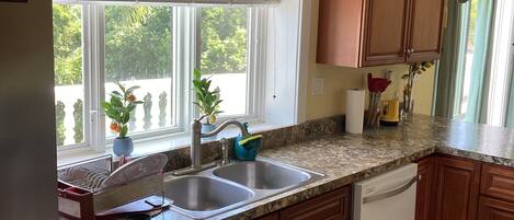 A kitchen with wooden cabinets, a stainless steel sink, and a dish drying rack.