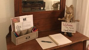 Un escritorio de madera con un espejo, un cartel de bienvenida, una libreta y un bolígrafo.