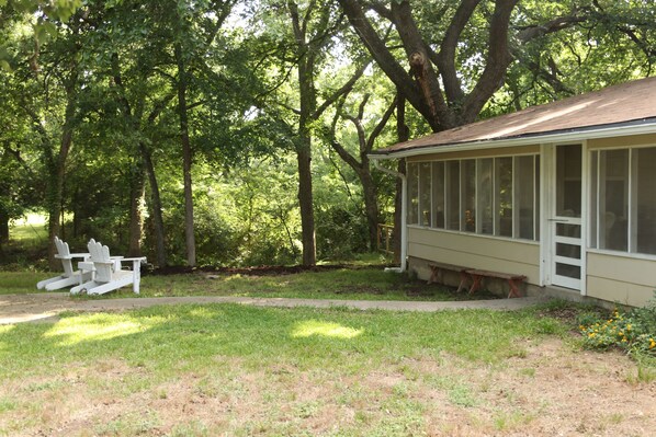 A house with a covered porch, surrounded by trees and a grassy yard. - Shady Acres Farm (Waco)