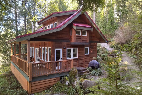 Eine Holzhütte mit Balkon, umgeben von dichtem Wald.
