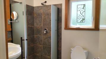 Une salle de bain avec douche, toilettes et lavabo.