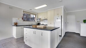 Una cocina moderna con armarios blancos, encimera de granito y microondas integrado.