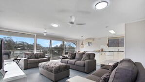 Una sala de estar moderna con sofás grises, una mesa de centro y un televisor. Hay un balcón con vistas a la ciudad.