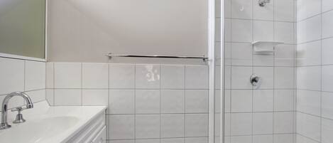 A bathroom with a white sink, mirror, and shower.