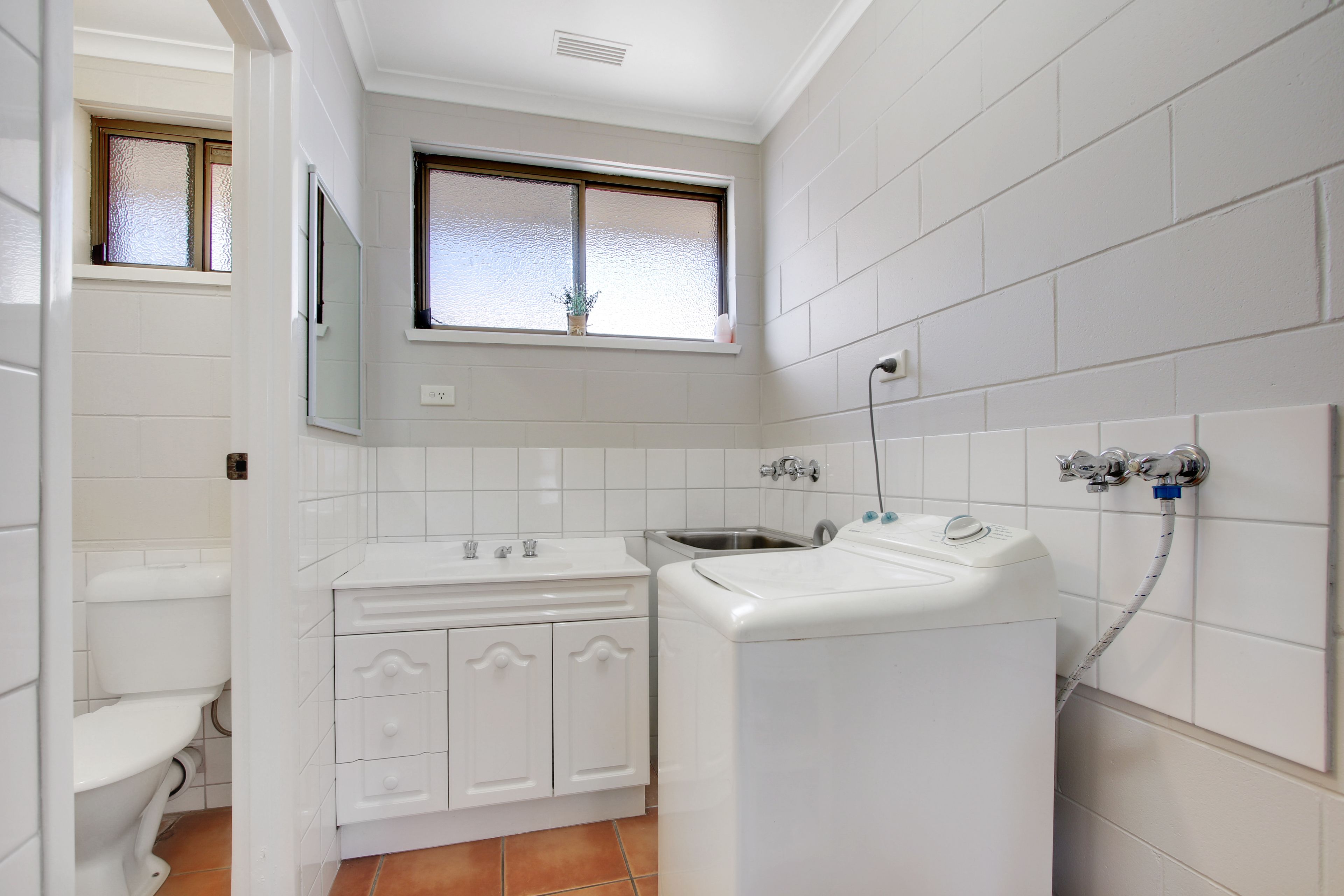 A compact bathroom with a toilet, sink, and washing machine.