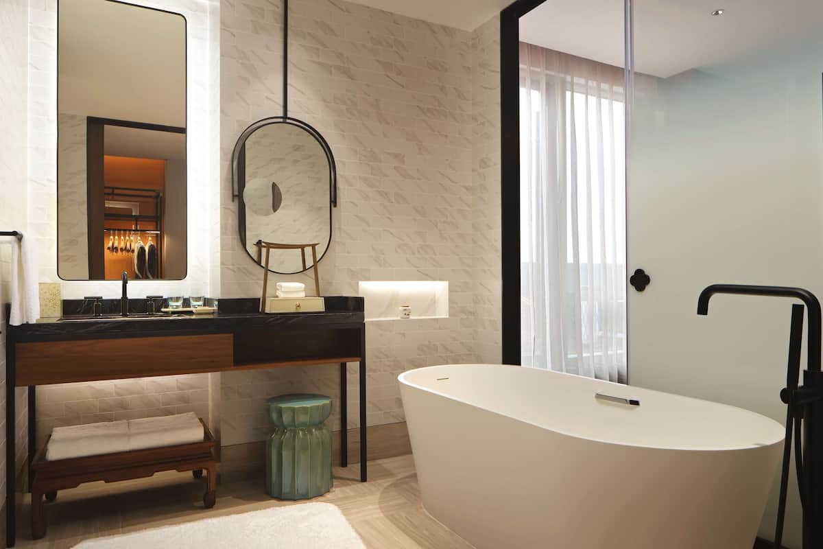 A modern bathroom with a freestanding bathtub, a vanity with a mirror, and a bench.