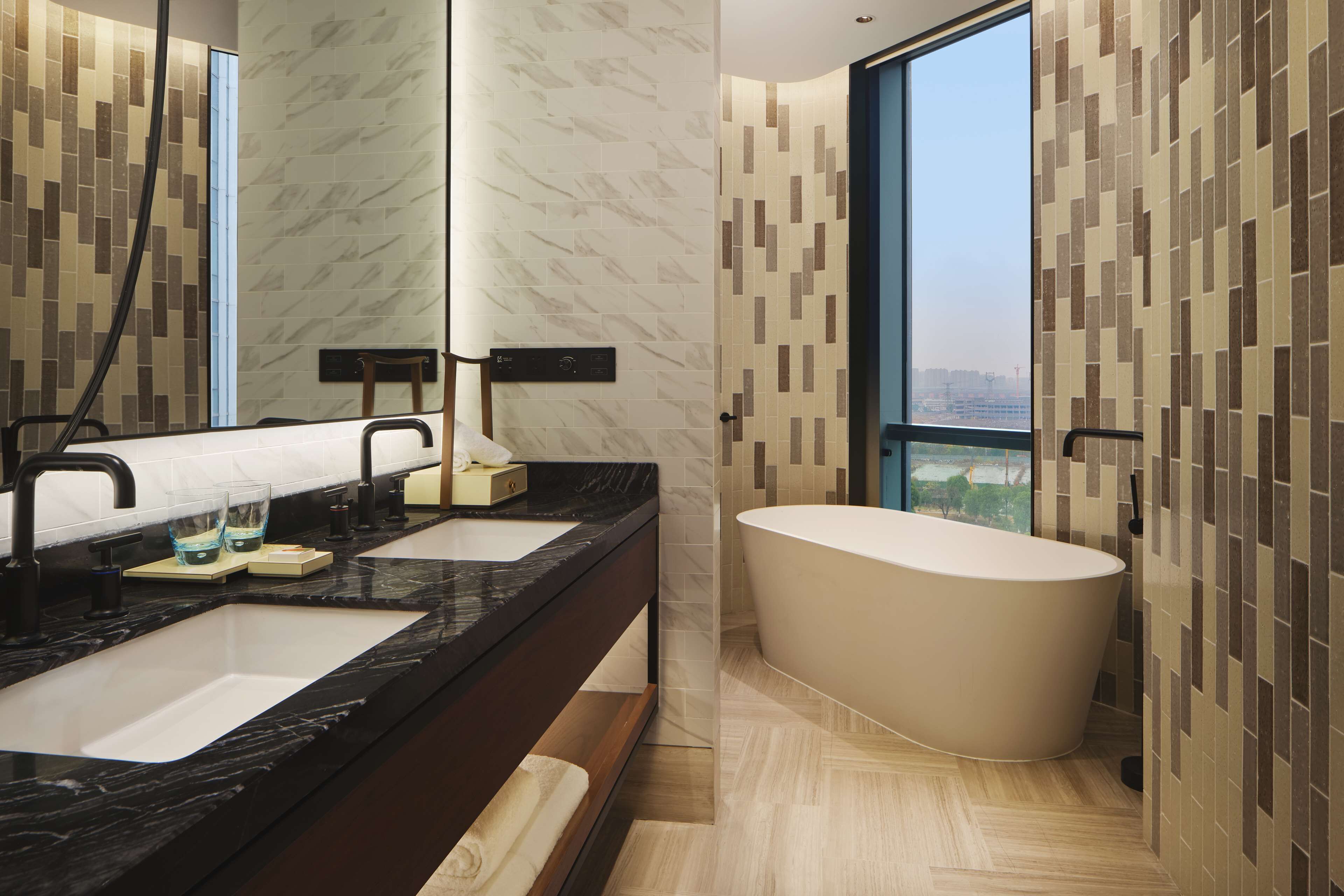 Un bagno moderno con due lavandini, un grande specchio e una vasca freestanding.