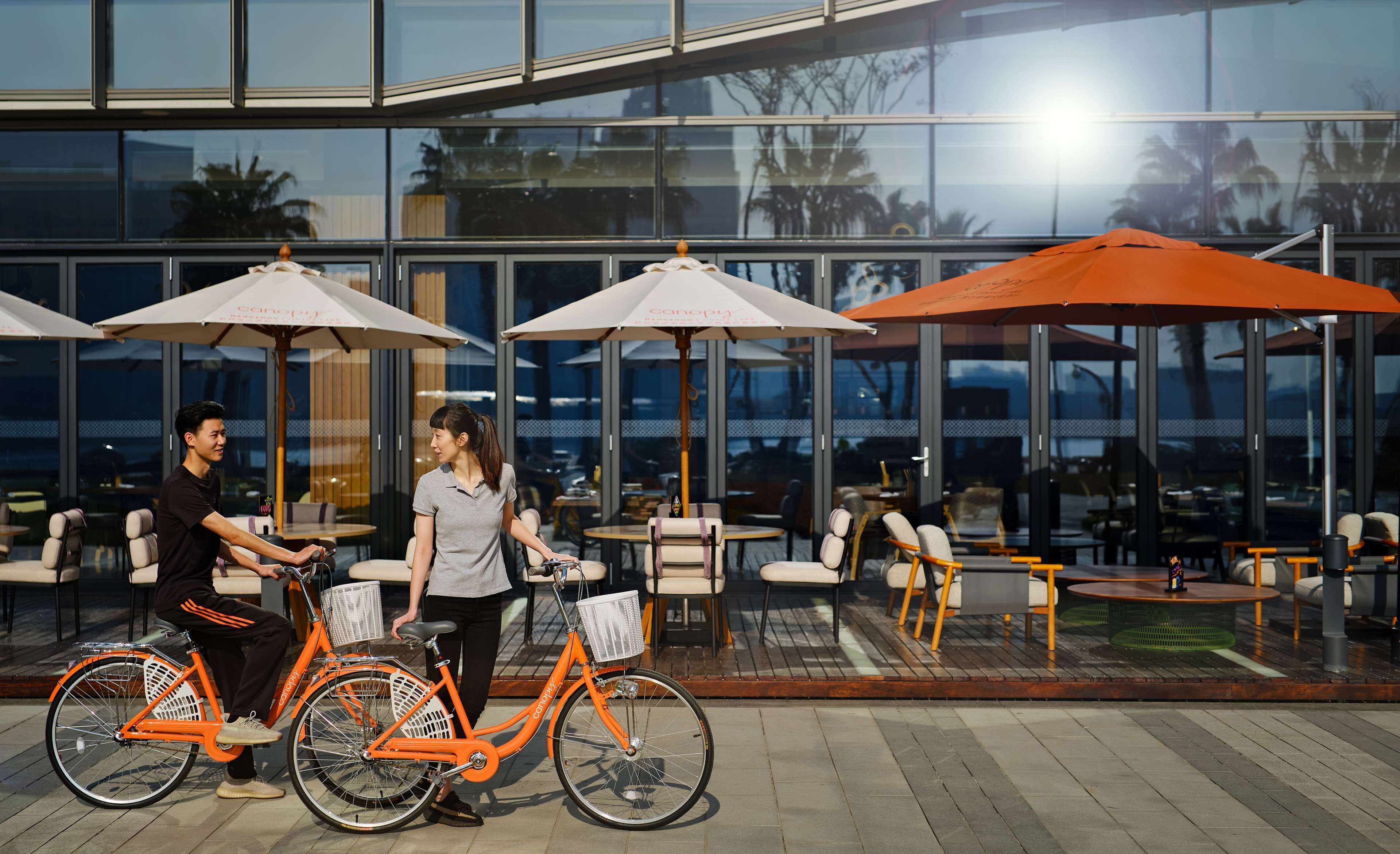 An outdoor seating area with tables and chairs, a bicycle, and umbrellas.
