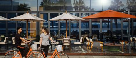 An outdoor seating area with tables and chairs, a bicycle, and umbrellas.