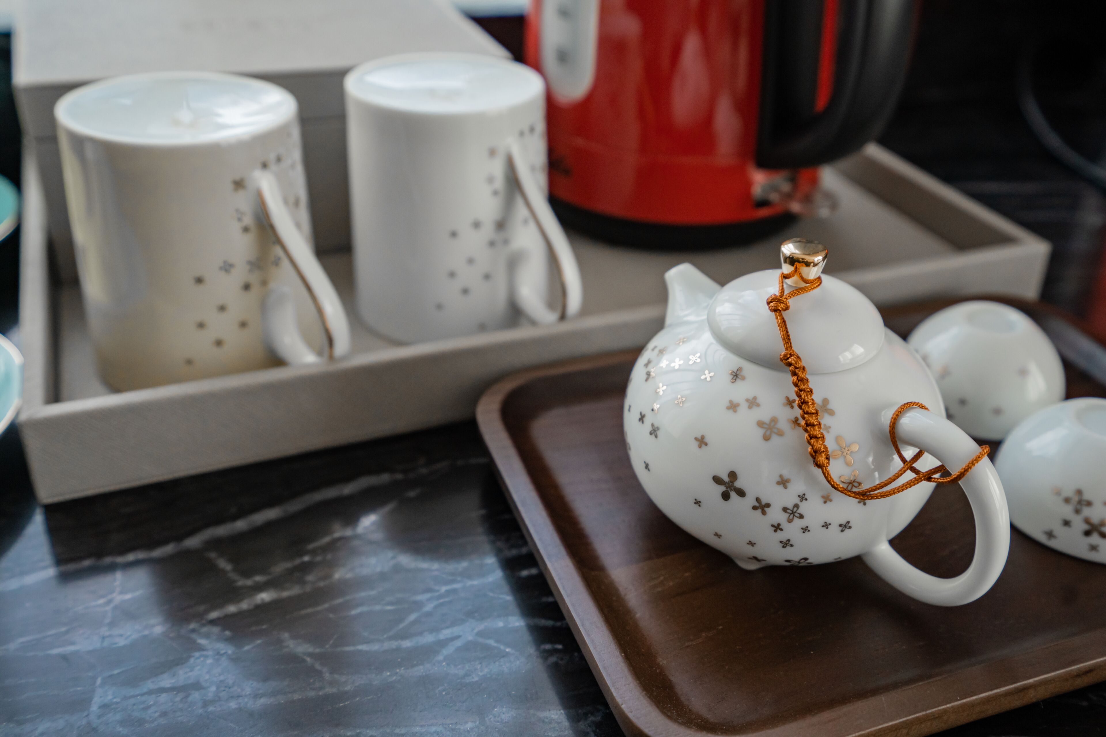 A tray with a teapot and two cups on a marble countertop.